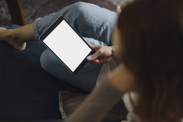 Frau sitzt auf einer Couch und benutzt ein digitales Tablet - JOSF04057