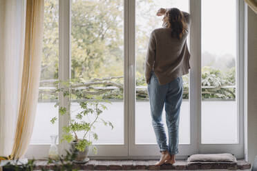 Frau schaut aus dem Fenster, Rückansicht - JOSF04065