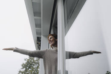 Frau prüft das Wetter und hält die Hand aus dem Fenster - JOSF04090