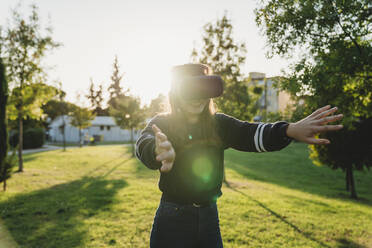 Junge Frau schaut durch VR-Headset im Park - CUF53907