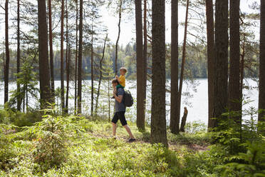 Vater nimmt seinen Sohn im Wald huckepack, Finnland - CUF53980