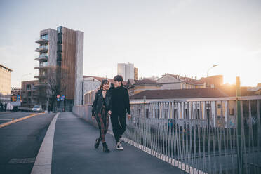 Trendy couple walking over bridge, Milan, Italy - CUF54087