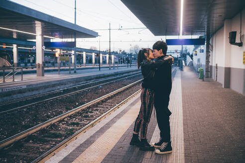 Junges Paar küsst sich auf dem Bahnsteig eines Bahnhofs, Mailand, Italien - CUF54112