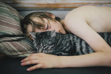 Boy sleeping with cat - JOHF04910