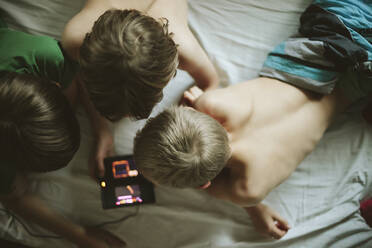 Boys using cell phone in bed - JOHF04928