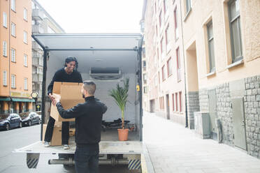 Männliche und weibliche Umzugshelfer entladen Kiste vom LKW auf der Straße in der Stadt - MASF15318