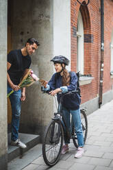 Eine Frau zeigt einem männlichen Kunden bei der Auslieferung eines Blumenstraußes ihr Mobiltelefon - MASF15334