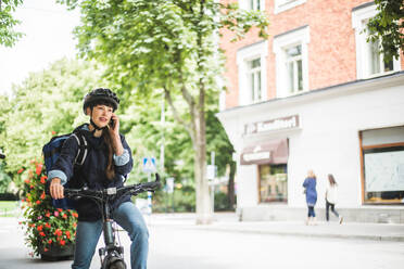 Food delivery woman talking on smart phone at street in city - MASF15343