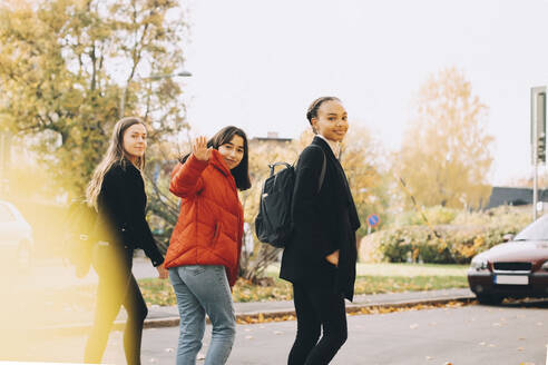 Porträt von lächelnden Teenager-Freunden, die gemeinsam auf einer Straße in der Stadt spazieren gehen - MASF15374