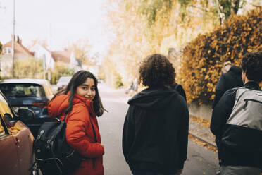 Porträt von Teenager-Mädchen zu Fuß mit Freunden auf der Straße in der Stadt während des sonnigen Tages - MASF15381