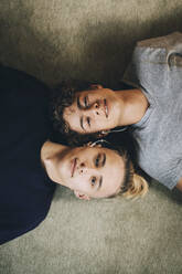 Direkt über dem Porträt von Teenagern, die zu Hause zusammen auf einem Teppich liegen - MASF15399