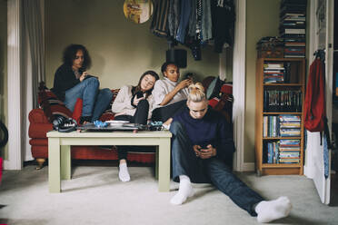 Distracted friends using smart phones while sitting together at home - MASF15423
