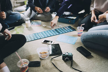 Eine kleine Gruppe von Freunden spielt Brettspiele, während sie zu Hause auf dem Boden essen - MASF15436