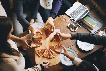 High angle view of friends taking slices of pizza at dining table - MASF15451