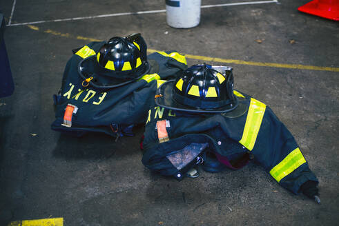 Uniformen und Helme von Feuerwehrleuten in einer Feuerwache, New York, Vereinigte Staaten - OCMF00944