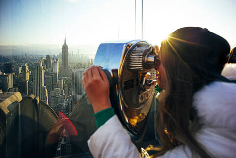 Woman on Top on the Rock looking through binoculars, New York City, United States stock photo