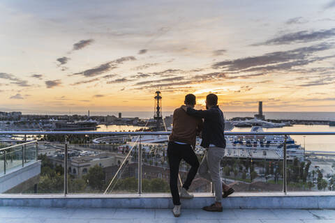 Schwules Paar auf Aussichtspunkt über der Stadt mit Blick auf den Hafen, Barcelona, Spanien, lizenzfreies Stockfoto