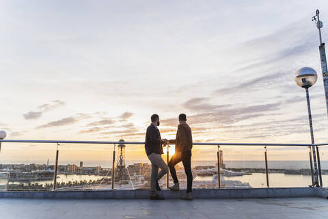 Schwules Paar auf Aussichtspunkt über der Stadt mit Blick auf den Hafen, Barcelona, Spanien, lizenzfreies Stockfoto