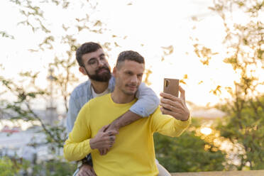 Zärtliches schwules Paar macht ein Selfie im Freien bei Sonnenuntergang - AFVF04444