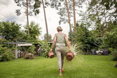 Rear view of woman walking in garden with plants - BFRF02139
