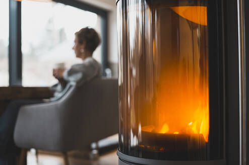 Frau sitzt am Kamin zu Hause - BFRF02141