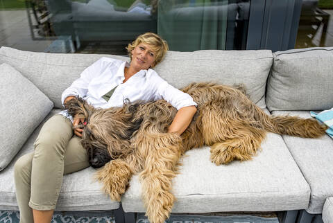 Woman relaxing with dog on terrace at home stock photo