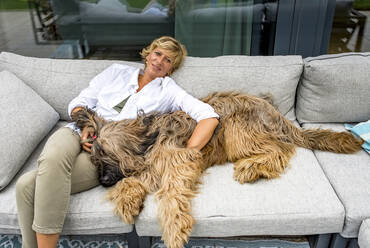 Frau entspannt sich mit Hund auf Terrasse zu Hause - BFRF02147