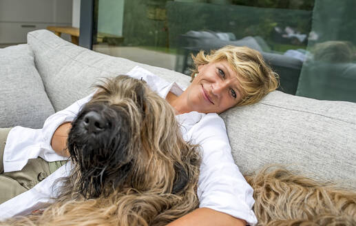 Porträt einer Frau, die sich mit ihrem Hund auf einer Terrasse zu Hause entspannt - BFRF02148