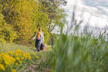 Frau geht mit Hund auf einem Feld spazieren - BFRF02151
