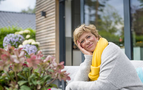 Porträt einer lächelnden Frau, die sich auf einer Terrasse zu Hause entspannt, lizenzfreies Stockfoto