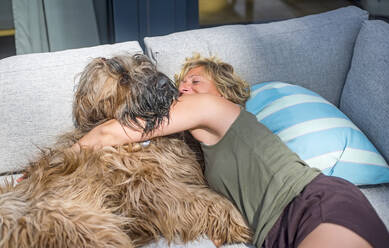 Frau kuschelt mit Hund auf der Terrasse zu Hause - BFRF02158
