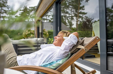 Woman relaxing in deckchair on terrace at home - BFRF02159