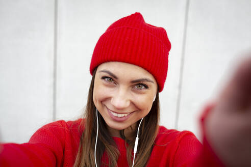 Frau mit rotem Pullover und Schlapphut vor einer Mauer - HMEF00701