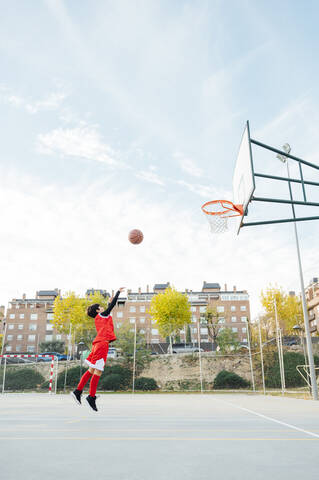 Junge spielt Basketball auf einem Platz im Freien, lizenzfreies Stockfoto