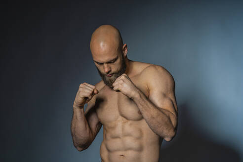Athlet mit nacktem Oberkörper in Boxerpose im Studio - DLTSF00311
