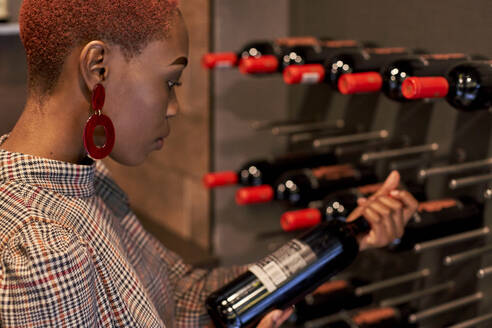 Young woman with short haircut choosing a wine in her cellar - VEGF01129