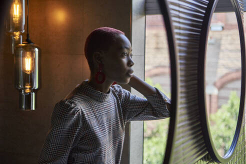 Young woman with short haircut looking to her reflection - VEGF01130