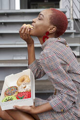 Young woman eating a doughnut from the box - VEGF01148