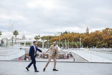 Elegantes schwules Paar geht Hand in Hand auf der Promenade, Malaga, Spanien - LJF01115