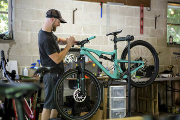 Mechanic repairing mountain bike in bicycle shop - CAVF70749