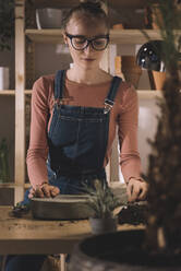 Woman planting in concrete pot at home - CAVF70751