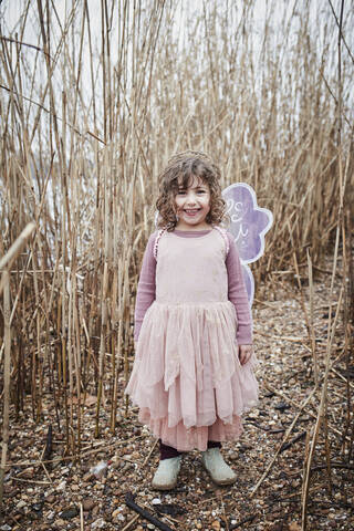 Porträt eines glücklichen kleinen Mädchens in der Natur, das als Schmetterling verkleidet ist, lizenzfreies Stockfoto