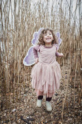 Portrait of happy little girl in nature dressed up as a butterfly - RORF01969