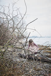 Little girl wearing pink fancy dress costume balancing on deadwood at riverside - RORF01973