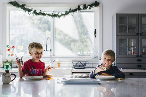 Glückliche Brüder beim Dessert am Weihnachtstisch zu Hause - CAVF70761