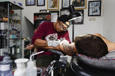 Tattoo artist tattooing customer's shoulder - CAVF70762