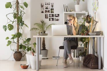 Kreative Geschäftsfrau in voller Länge mit Laptop im Büro - CAVF70766