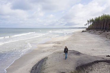 Russland, Kaliningrader Gebiet, Selenogradsk, Mann spaziert am Sandstrand der Ostseeküste - EYAF00760
