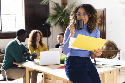 Portrait of a smiling woman in office with colleagues in background stock photo