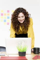 Smiling woman working on laptop at desk in office - FMOF00832